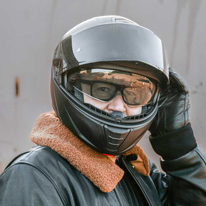 biker wearing black motorcycle helmet for men with glasses with visor flipped up