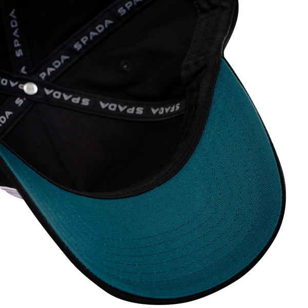 Teal and black Dean Harrison cap with 'Spada' branding on a white background
