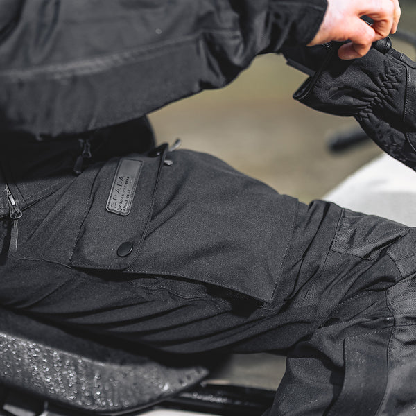 closeup of biker on motorbike wearing black motorcycle waterproof trousers