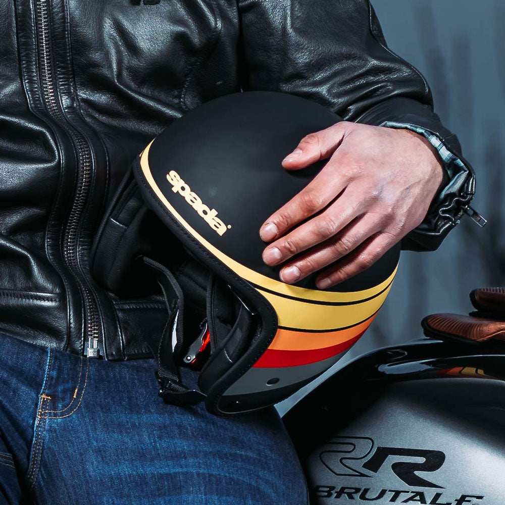 biker holding matte black and multicoloured open face motorcycle helmet