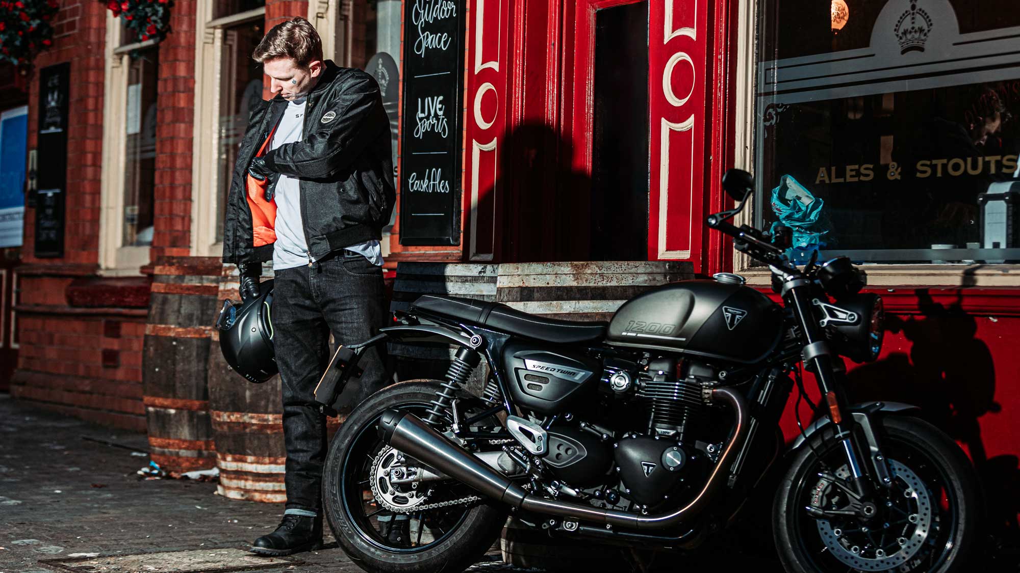 biker wearing black bomber jacket for men with motorbike outside cafe in birmingham