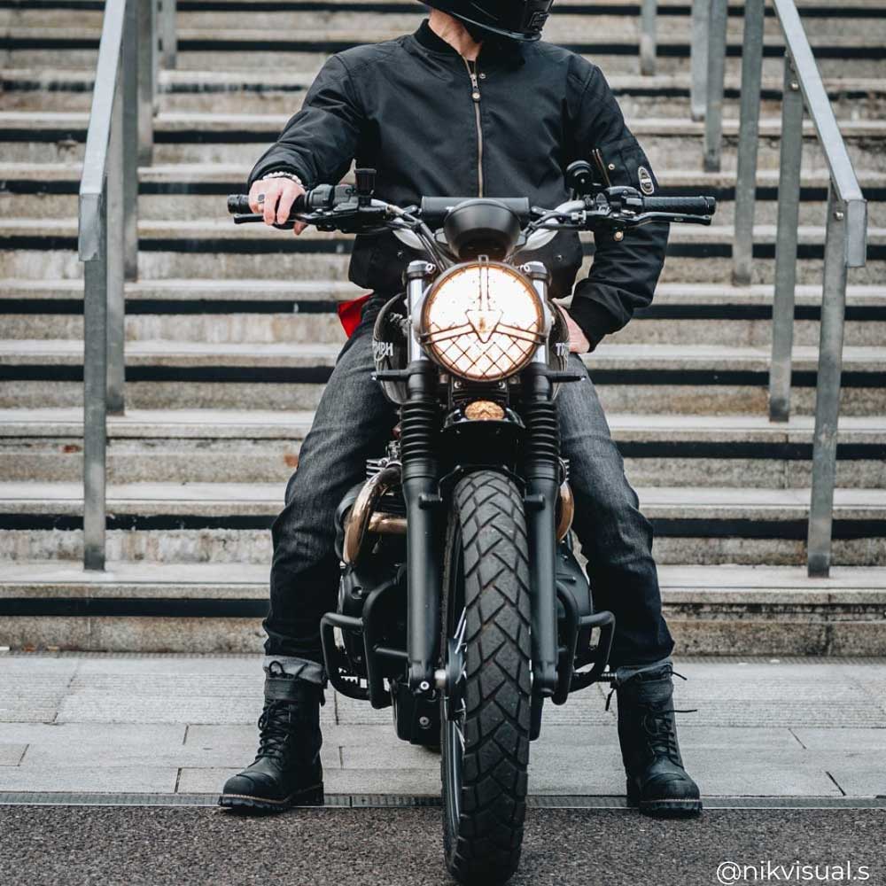 biker riding motorbike wearing black motorcycle gear including black boots for men and black bomber jacket