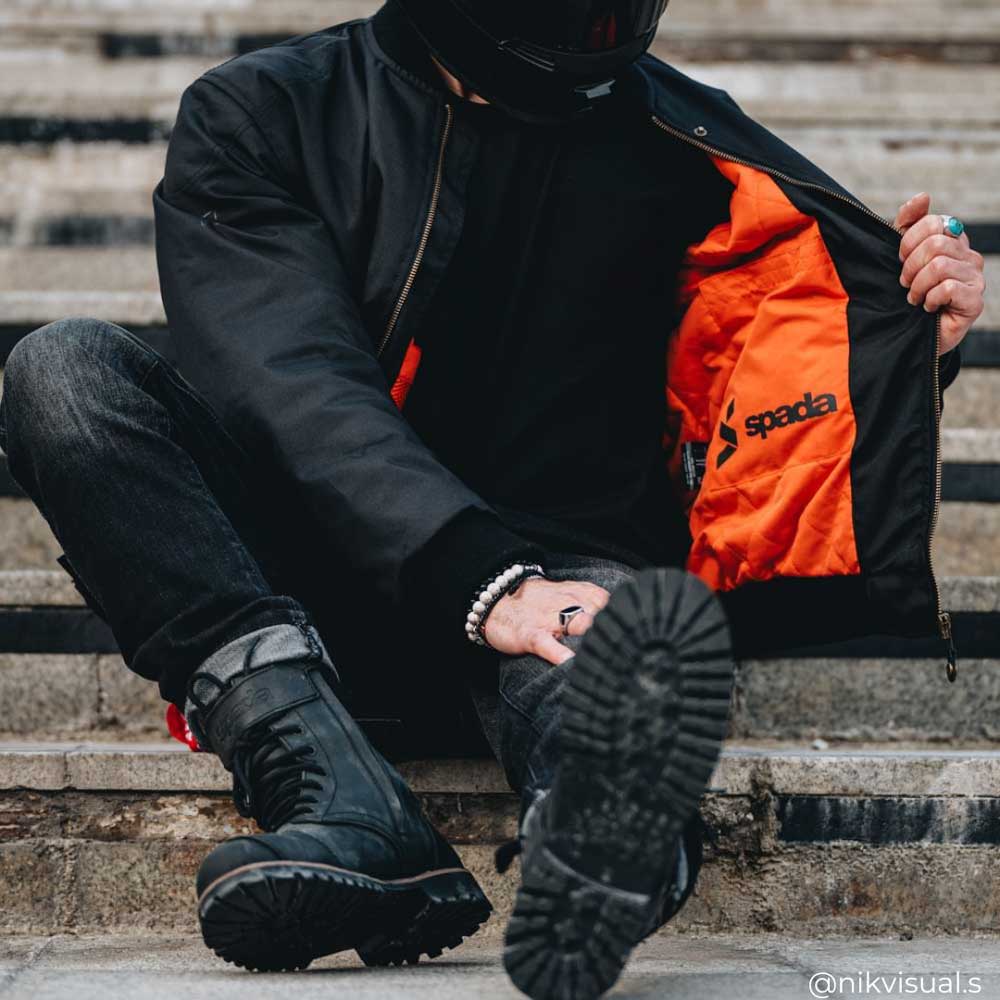 biker wearing black bomber jacket for men with orange lining inside