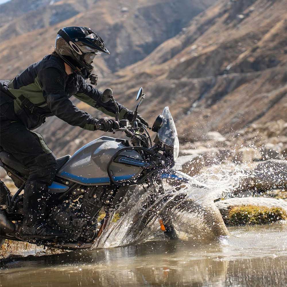 biker riding motorbike through lake with black and green waterproof motorcycle jacket