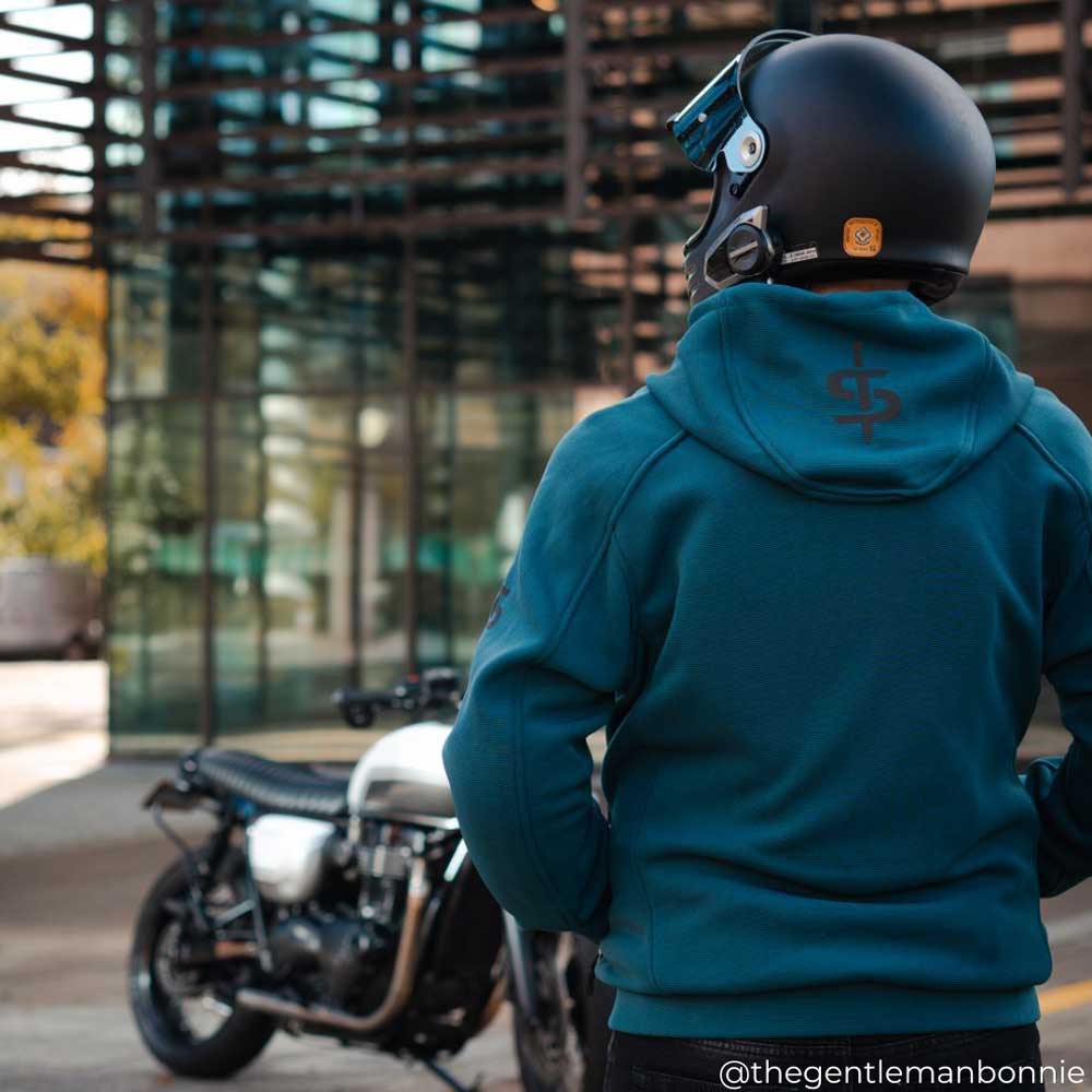 back of biker wearing blue motorcycle hoodie with black helmet and motorbike