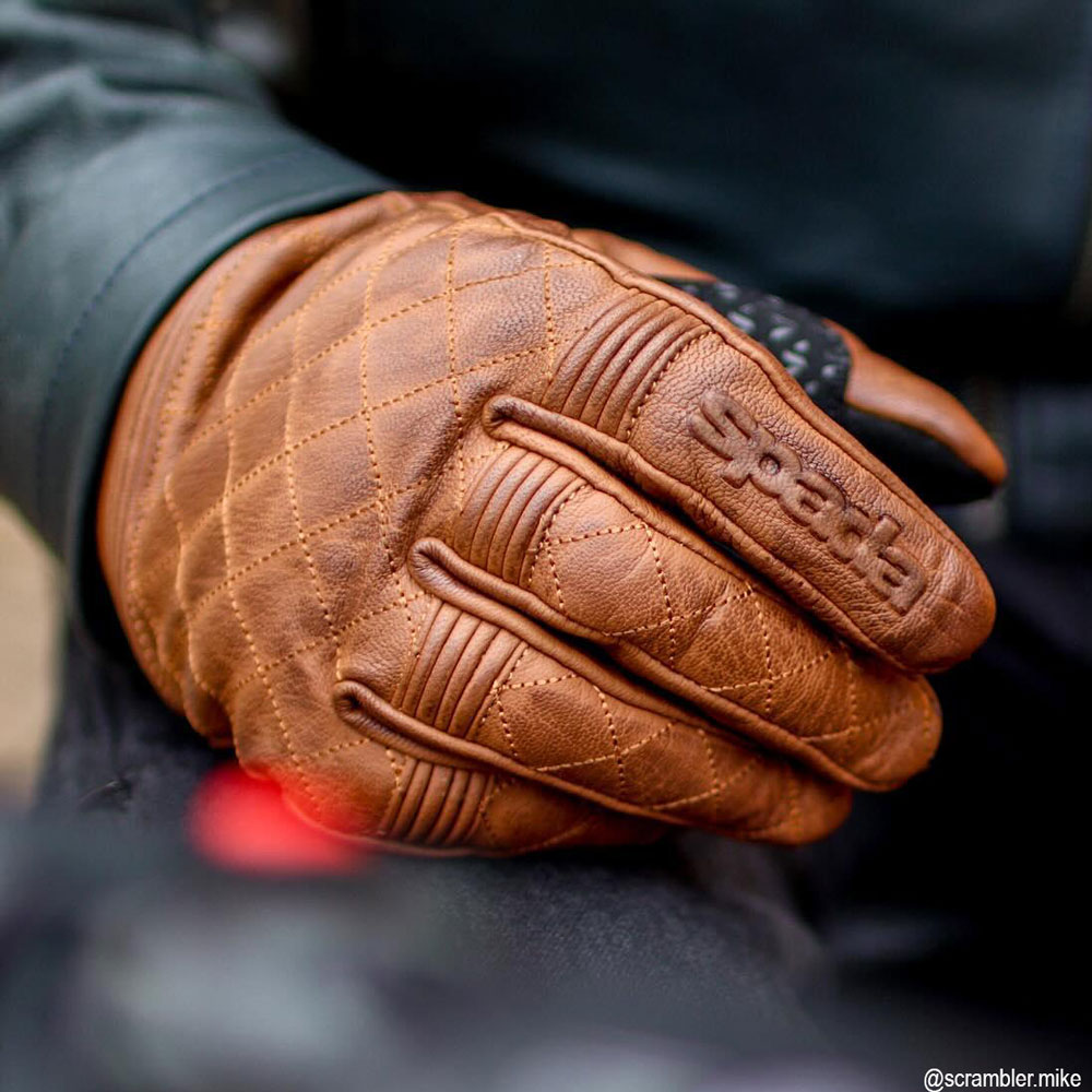 close up of biker wearing brown leather motorcycle gloves with cross stitching