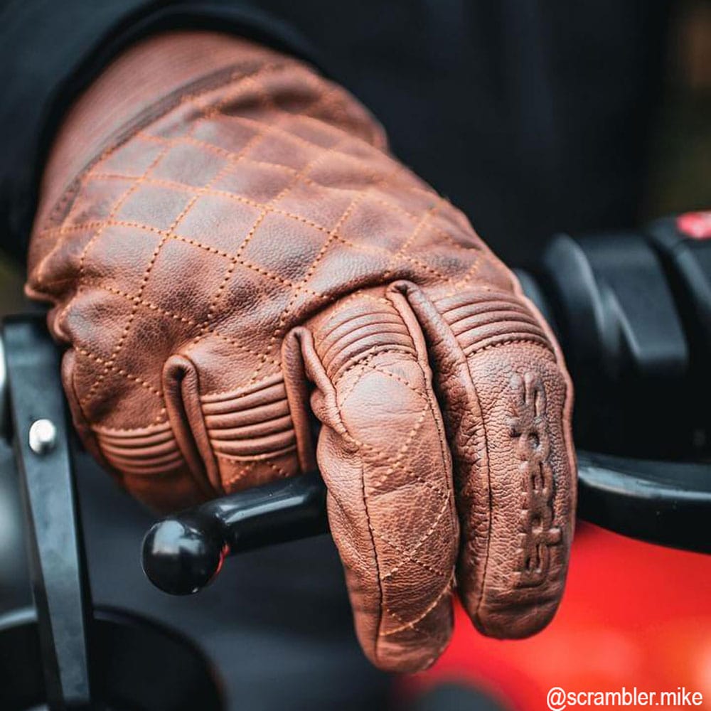 close up of biker wearing brown leather motorcycle gloves on motorcycle ride