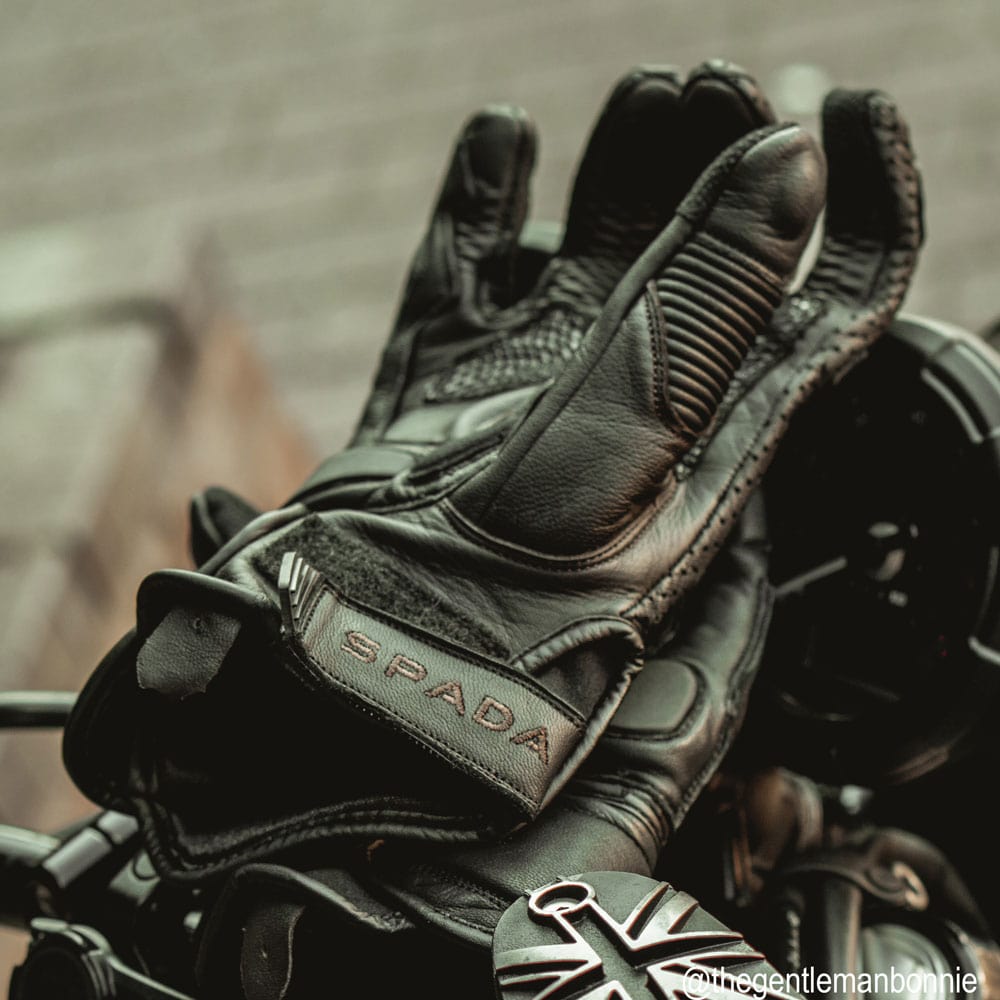 black leather motorcycle glove with brown detailed stitching sitting on a motorbike