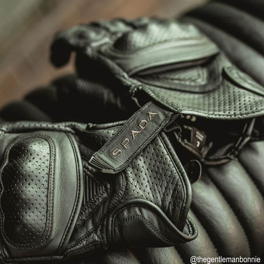 flat lay of black leather motorcycle gloves on a motorcycle with ventilation and knuckle protection