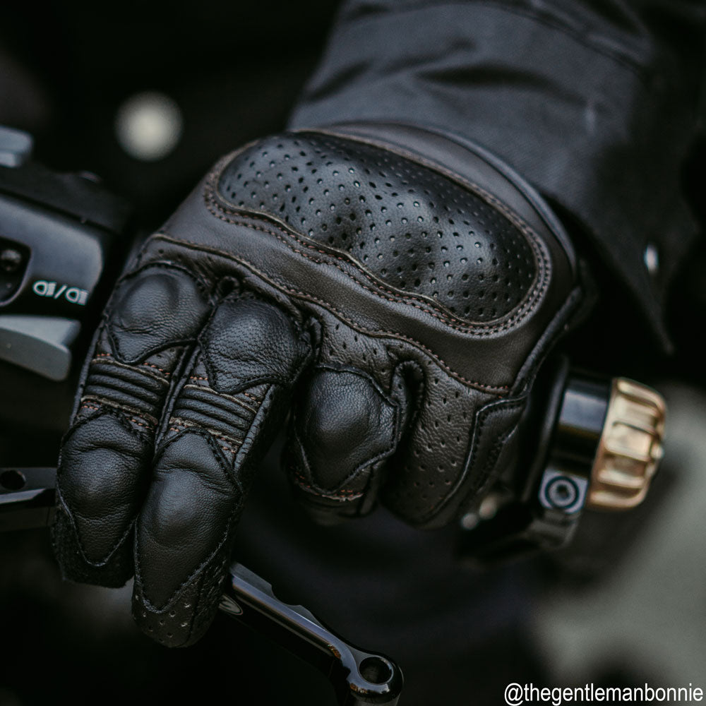 biker wearing black leather motorcycle gloves with brown stitching on a ride