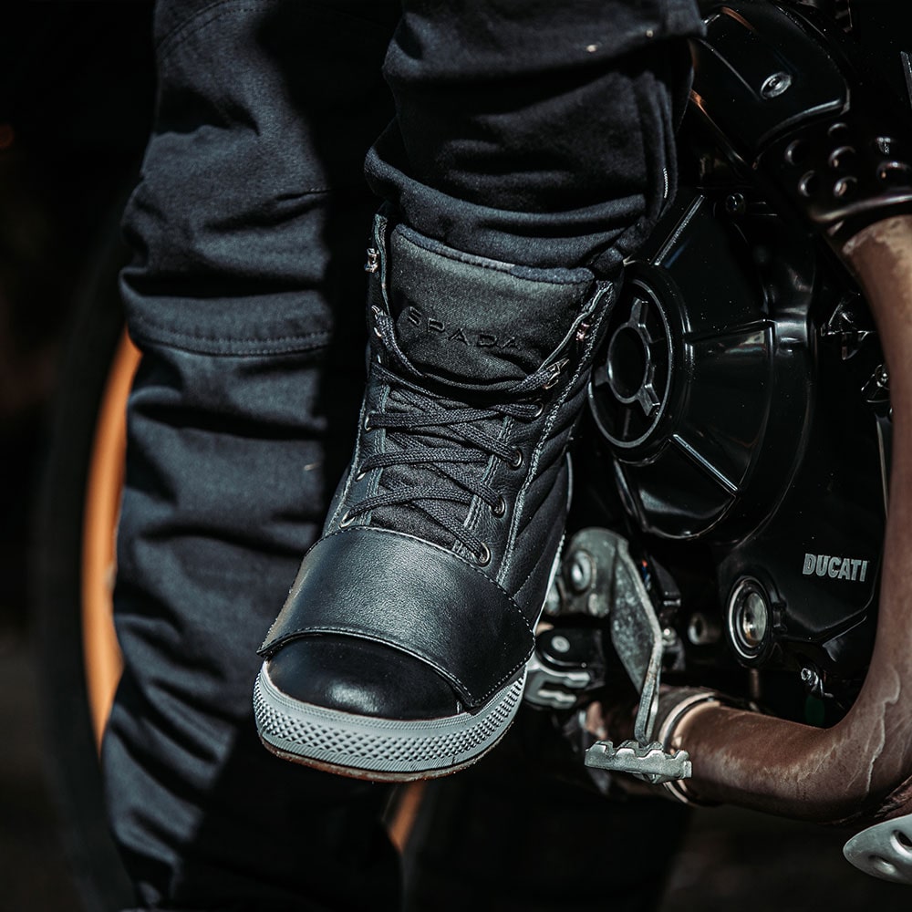 close up of biker wearing black leather motorcycle botos on a ride