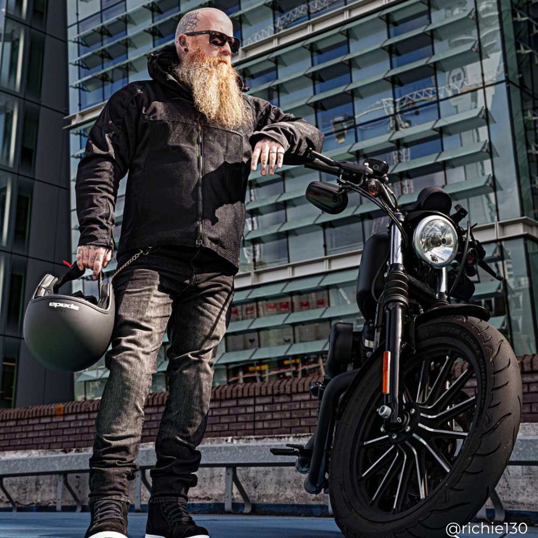 biker wearing black motorcycle jacket, black motorcycle jeans and black helmet with motorbike