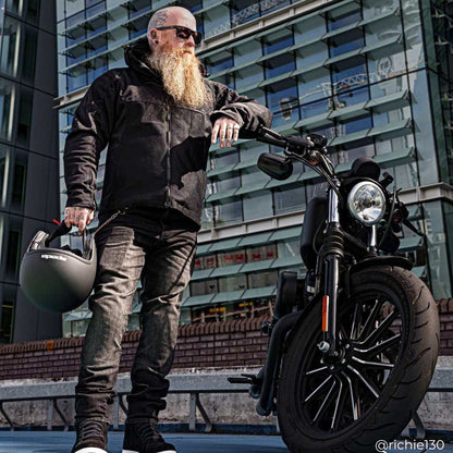 biker wearing black motorcycle jacket, black motorcycle jeans and black helmet with motorbike