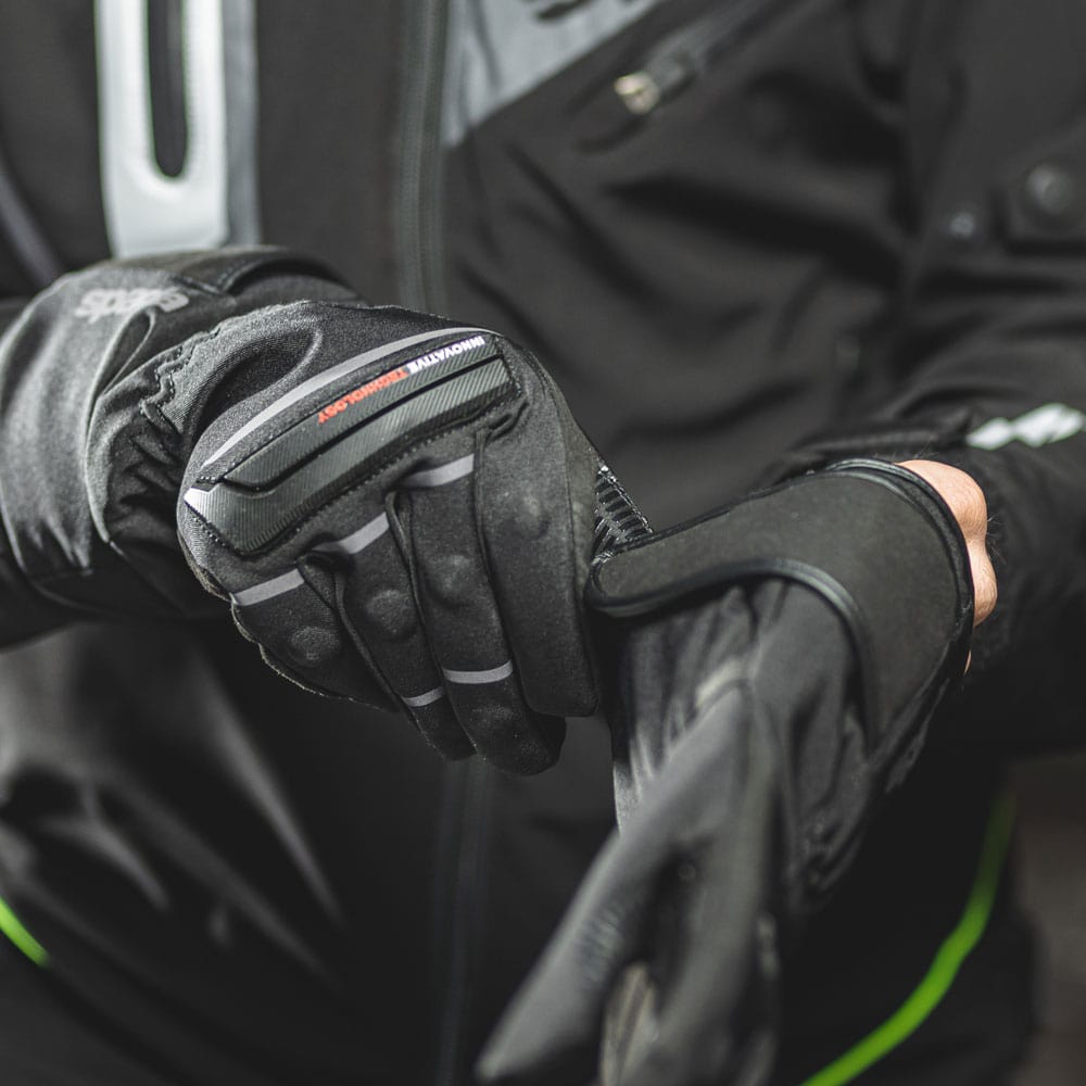 biker putting on black textile waterproof motorcycle gloves