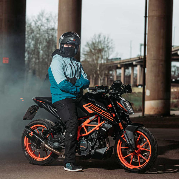 Male biker sitting on orange and black motorcycle wearing blue waterproof motorbike jacket, designed for men and built for all-weather riding