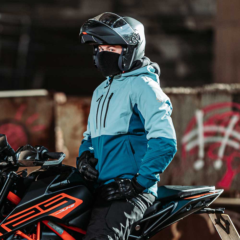 biker wearing motorcycle helmet and blue waterproof motorcycle jacket for men on motrobike