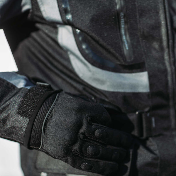 biker wearing black motorcycle gloves with matching jacket