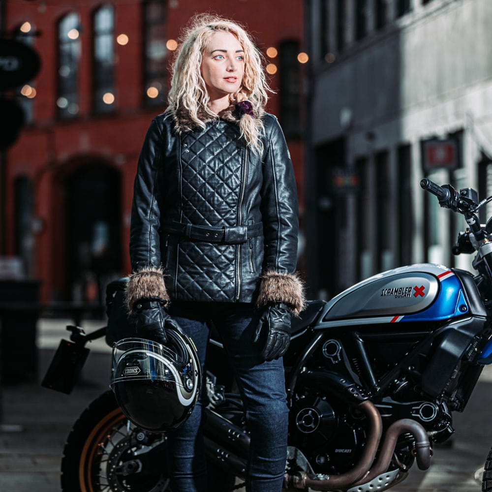 biker girl wearing black leather jacket with faux fur on motorbike