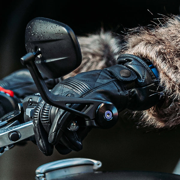 closeup of female biker wearing black leather gloves holding handle bar on motorbike
