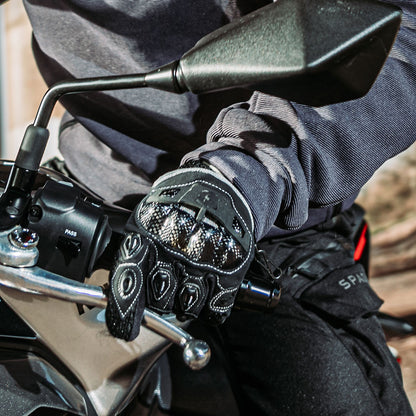 woman biker wearing black motorcycle gloves with white stitching and knuckle protection on a ride