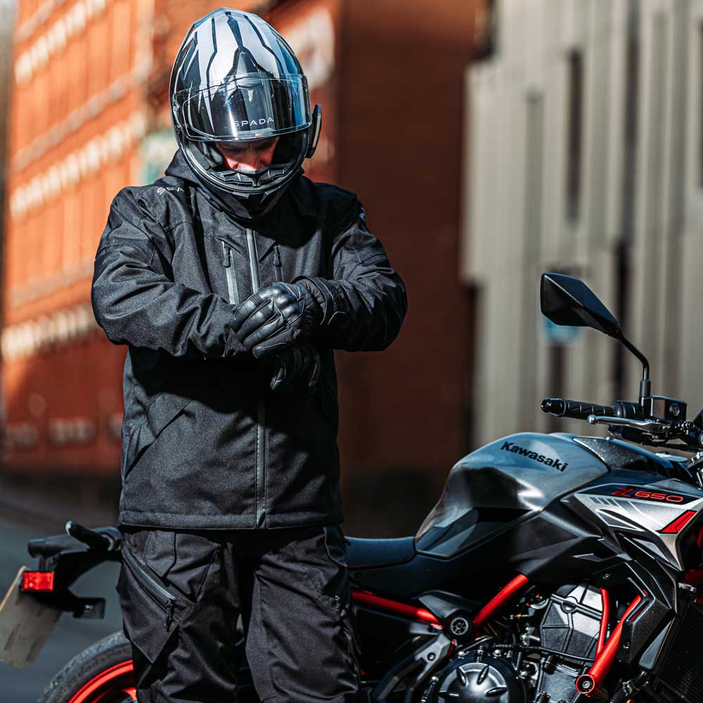 biker on the road wearing black waterproof motorcycle jacket with helmet and motorbike