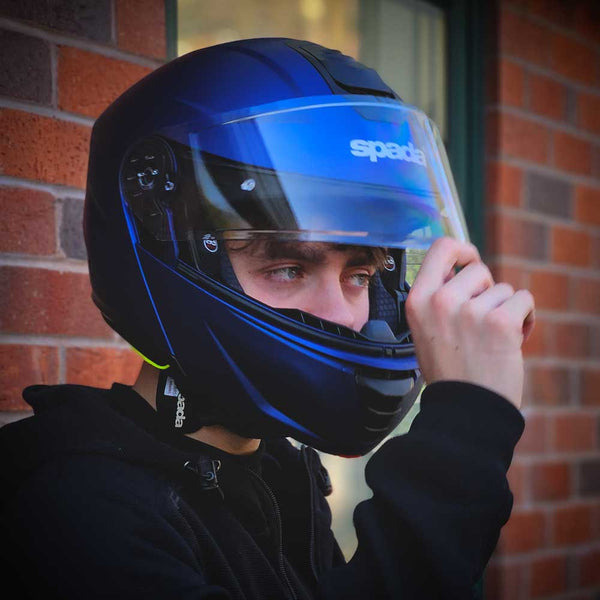 biker opening clear visor on blue motorbike helmet