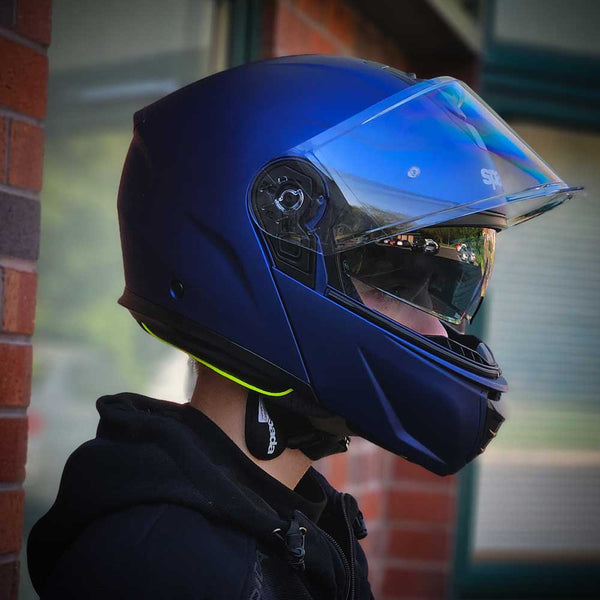 side profile of biker wearing matt blue motorbike helmet with integrated sun visor and a clear visor