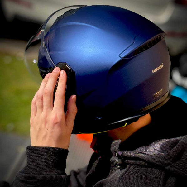 back of biker flipping visor on matt blue motorbike helmet