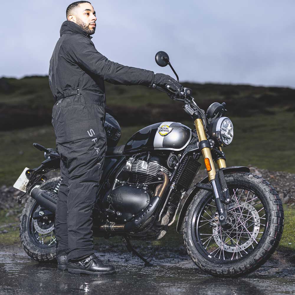 biker with motorbike wearing full black motorbike gear in nature