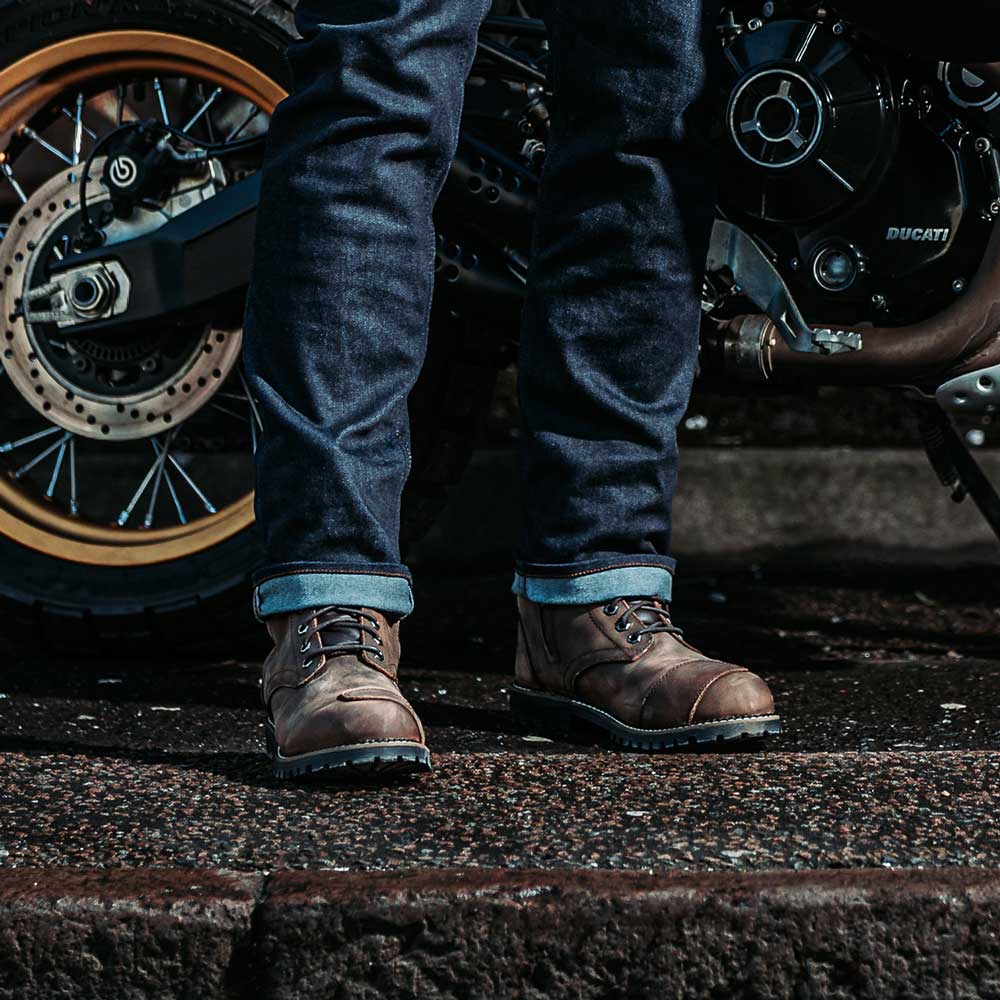 biker wearing brown motorcycle boots with blue motorcycle jeans on motorbike