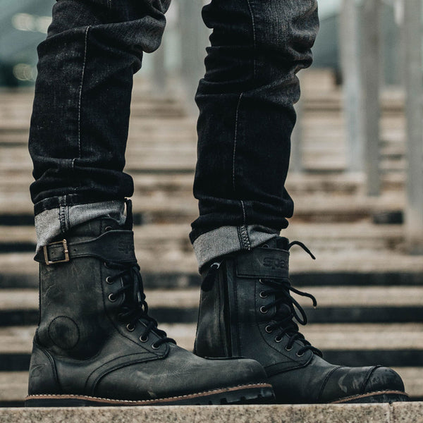 side view of man wearing black motorbike boots with jeans