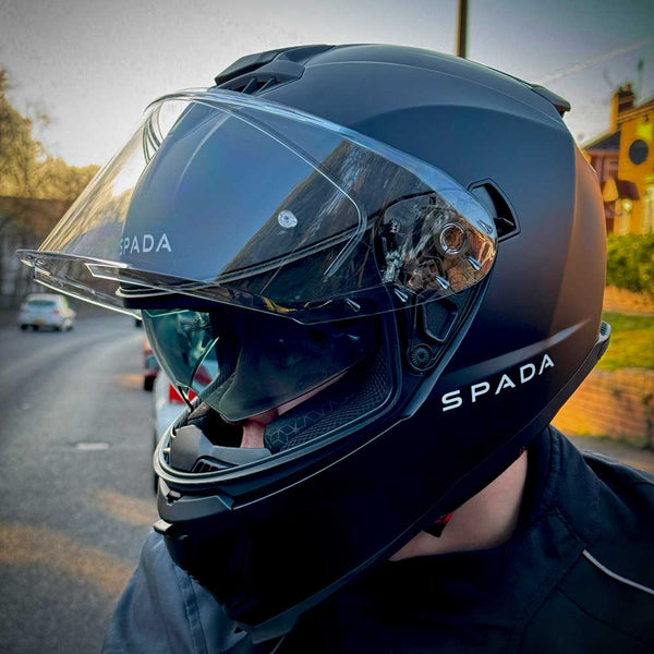 biker on the road wearing matte black motorbike helmet with integrated visor