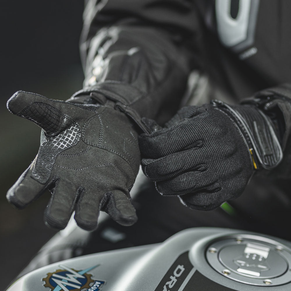 biker putting on black textile gloves for motorbike ride and close up of inside palm