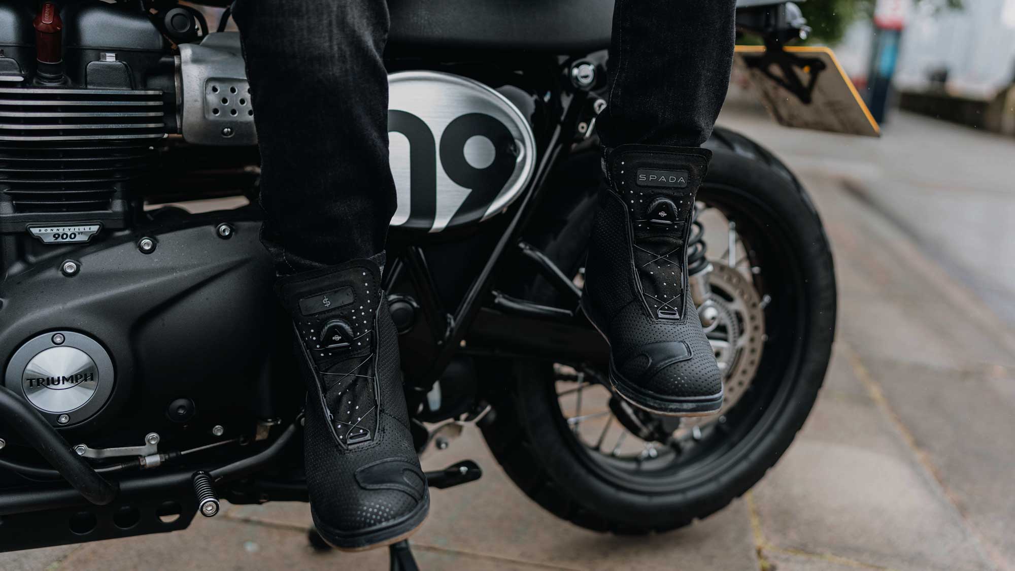 biker wearing black reflective motorcycle trainers on a black triumph motorcycle bike