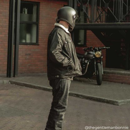 biker wearing trucker style black motorcycle jacket for men with black helmet and motorbike