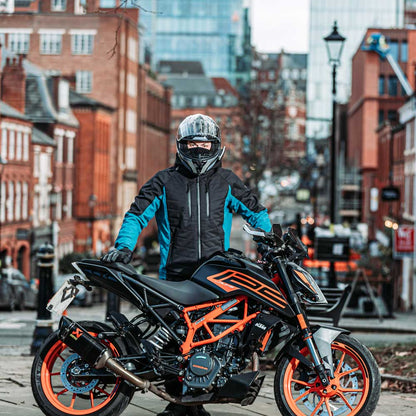 biker on black and orange motorbike wearing motorcycle helmet and black and blue jacket for men