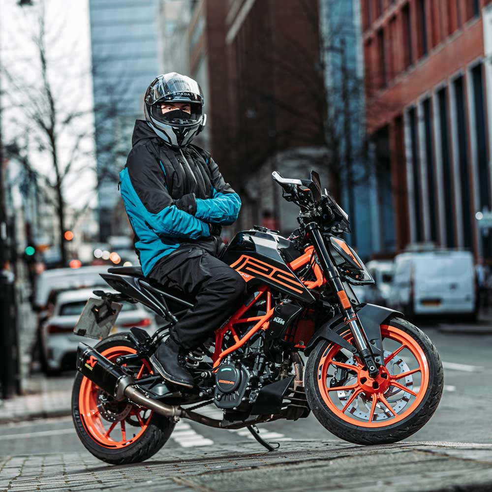 biker on motorbike wearing black and blue motorcycle gear in city riding