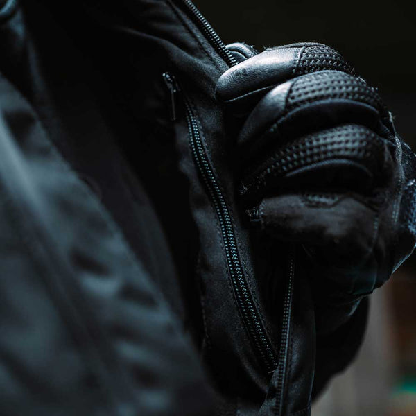 closeup of biker opening black quilted motorcycle jacket for men with black leather motorcycle gloves