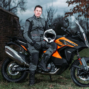 biker wearing full grey motorbike gear with white motorbike helmet
