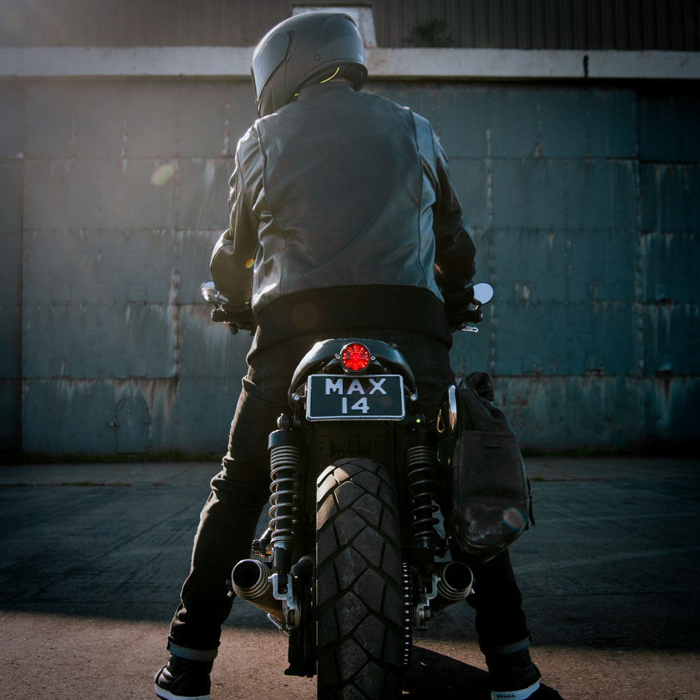 back of biker in all black leather jacket on motorbike