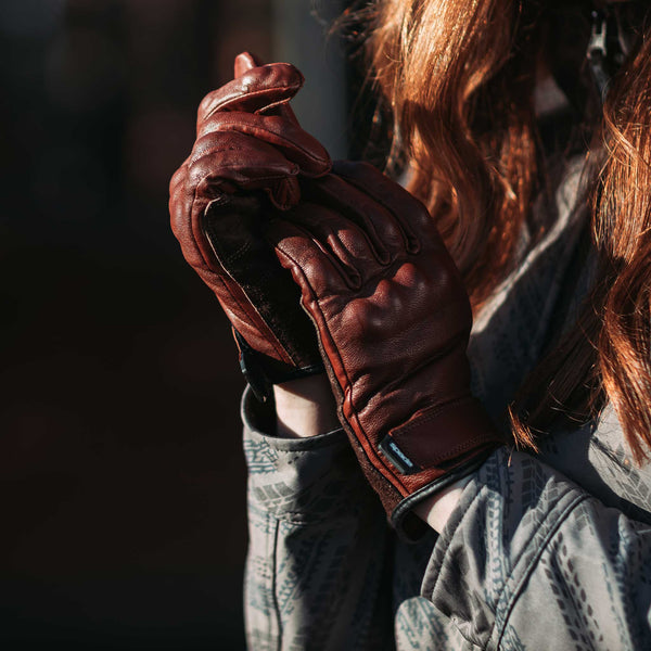 closeup of female biker wearing a pair of brown leather motorcycle gloves for women