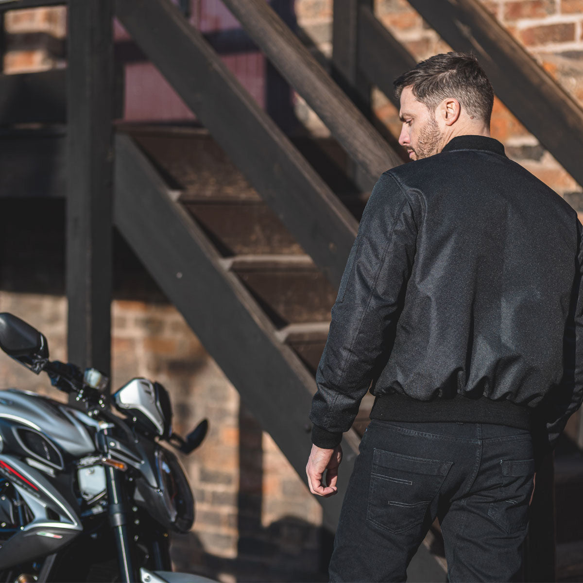 man wearing a black Spada bomber jacket for motorcycle riding with a classic and comfortable fit