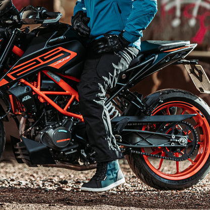 biker riding black and orange motorcycle wearing black protective riding trousers