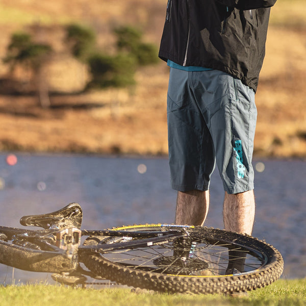 biker stood next to bike on the lake wearing blue shorts